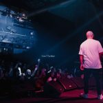 Rapper se apresenta em um palco iluminado diante de uma plateia durante um show.