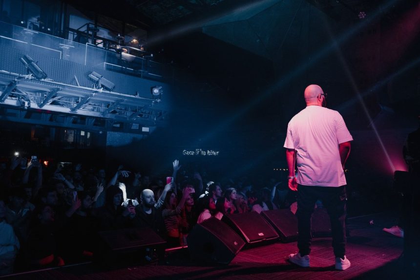 Rapper se apresenta em um palco iluminado diante de uma plateia durante um show.